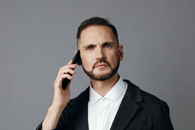 A professional man on a colored isolated background, conveys confidence and focus during a business call, showing calm, determined emotions and clear communication.
