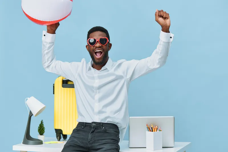 Lively happy cheerful man with sunglasses celebrating success in bright office studio with colorful accessories, holding a beach ball and smiling broadly. Casual style, positive vibe, modern workspace