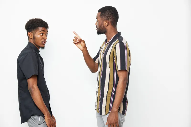 Two African American men engaging in a deep conversation, expressing emotions, and showcasing a moment of connection and understanding in a minimalistic setting.