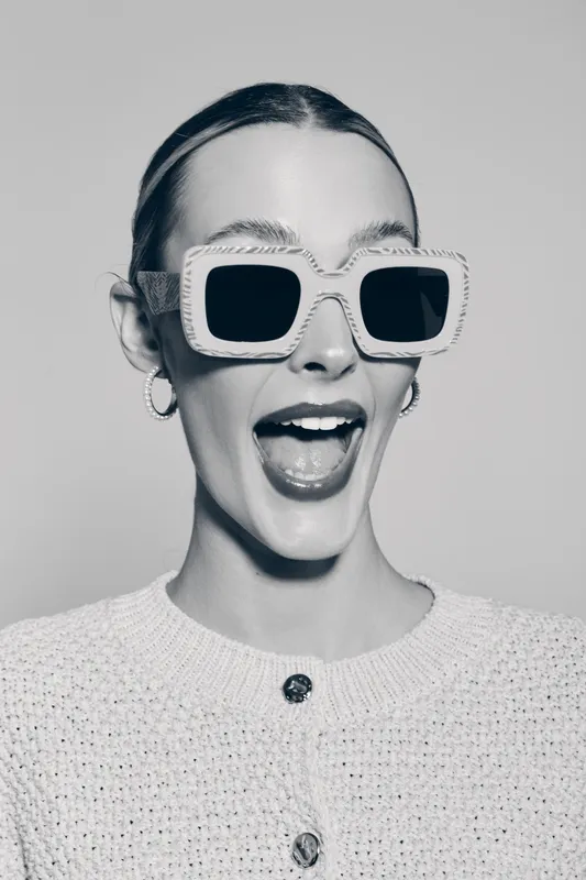 Happy white woman with fair skin wearing large sunglasses smiling with open mouth in studio. Concept of fashion lifestyle and joy.