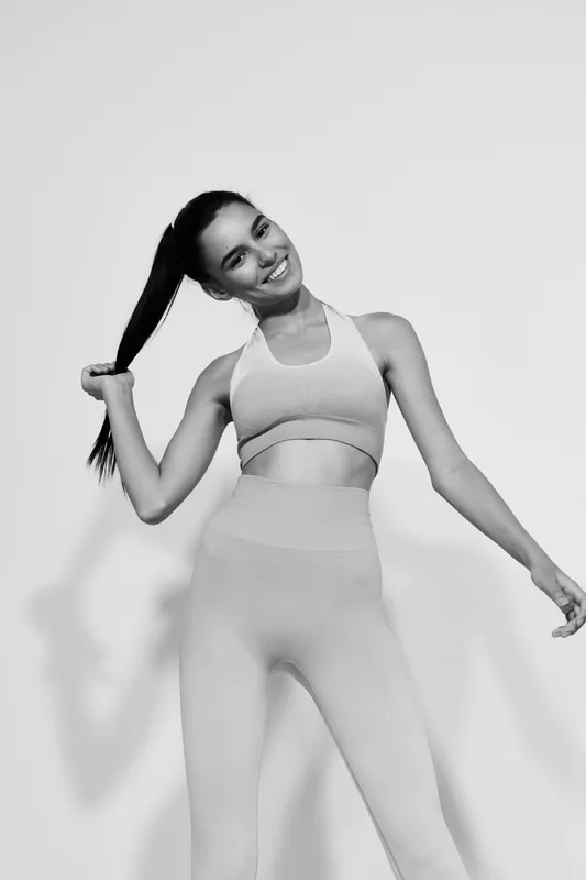 Woman sport fitness smiling in activewear, showing healthy lifestyle and positive energy, black and white photography with casual pose and bright lighting.