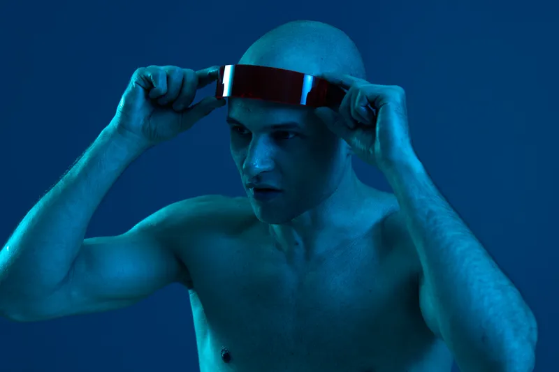 Bald man wearing a futuristic headset in a blue light setting, showcasing technology and innovation in a captivating manner. Perfect for technology-related themes.