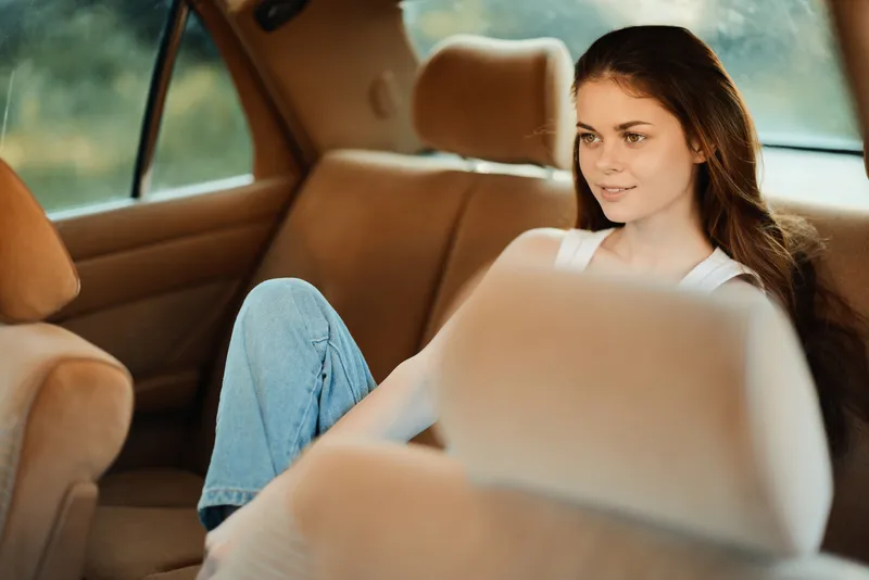 Young woman in a car, relaxed and contemplative, wearing casual clothing, with soft lighting and a natural background, embodying a serene summer vibe.