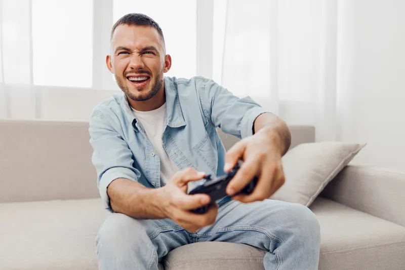 A relaxed man enjoys playing video games at home, showcasing the balance of leisure and digital engagement. This scene highlights modern lifestyle choices.