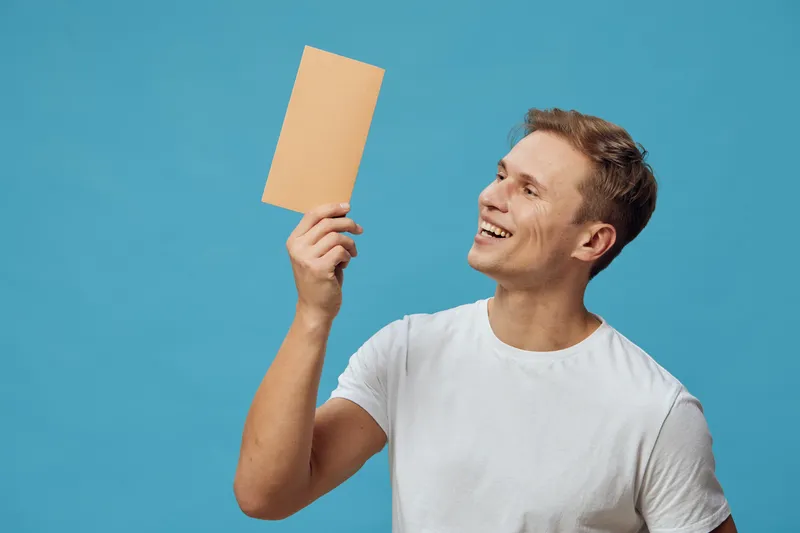 smiling young caucasian man hold envelope look happy wear white t-shirt blue background digital detox communication concept