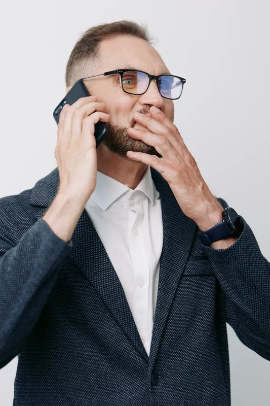 A professional businessman in a blazer speaks on a mobile phone, displaying a focused, thoughtful expression against an isolated colored background.