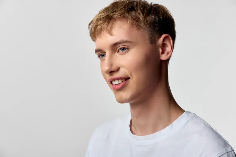 Man with a gentle smile, wearing a white t shirt, photographed in a bright studio, conveying an approachable, relaxed mood ideal for lifestyle, corporate communications and friendly brand storytelling