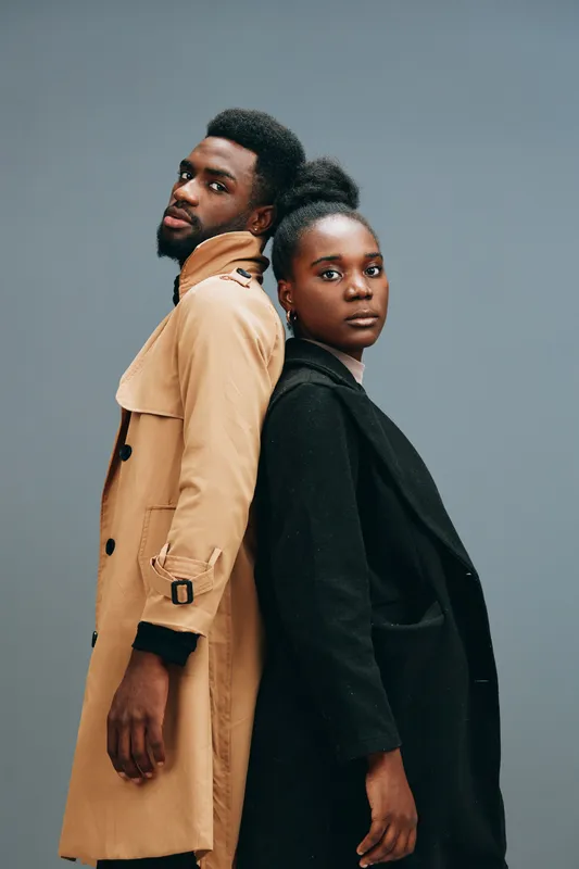 Stylish urban couple in fashionable outfits showcasing confidence against a gray background, ideal for fashion and lifestyle themes
