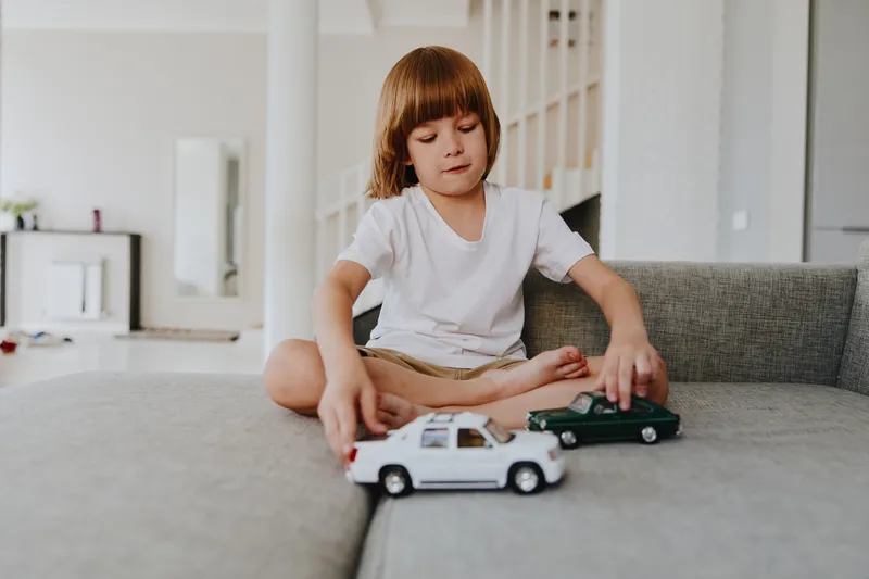 Young boy playing with toy cars in a cozy living room. The scene radiates joy, creativity, and a sense of childhood wonder.