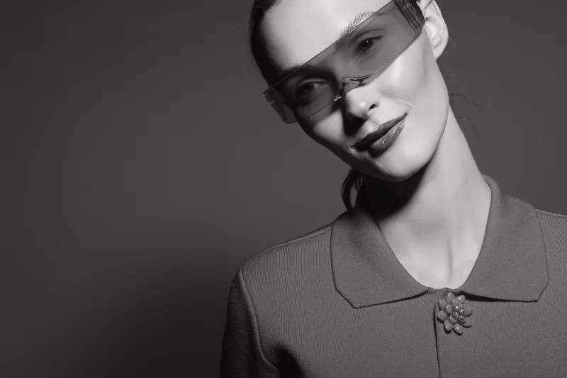 Young caucasian woman with pale skin wearing retro sunglasses and textured shirt with collar in studio black and white portrait.