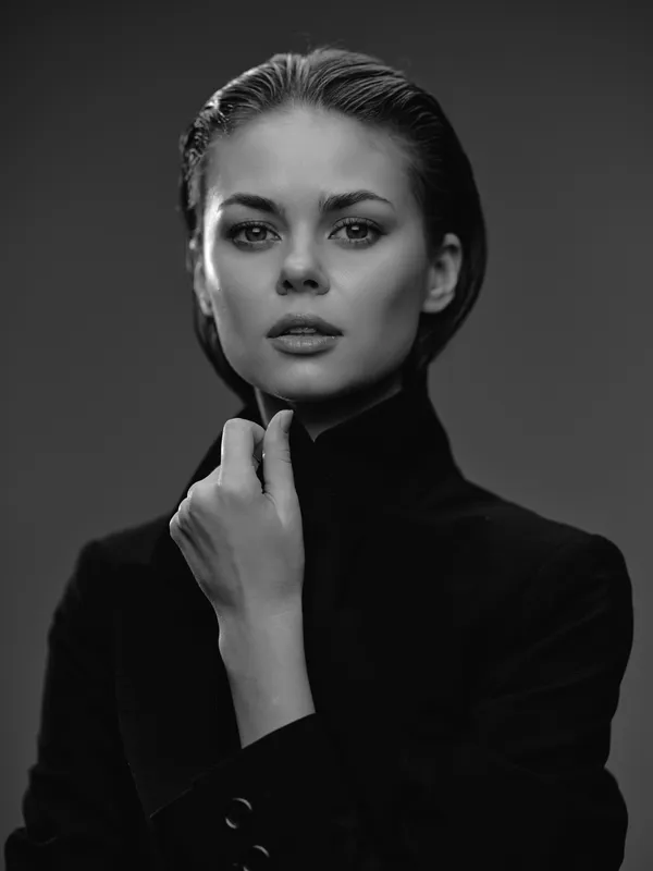 Black and white portrait of a thoughtful woman wearing a dark turtleneck against a gray background
