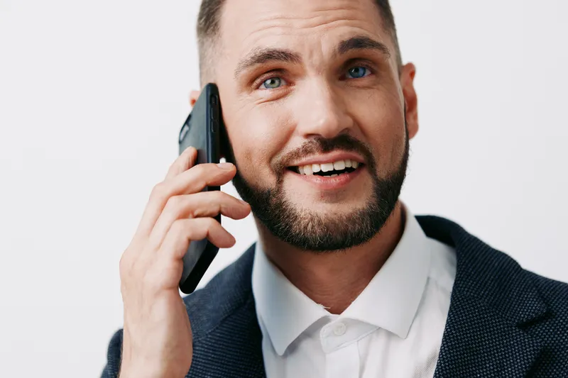 A professional man on a colored isolated background, speaking on a cellphone with a confident, friendly expression, showcasing business readiness and communication skills.