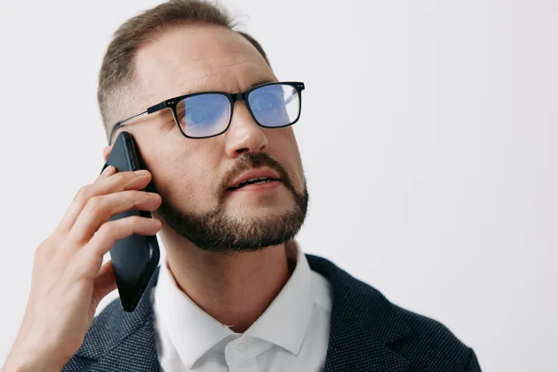 Business professional man on a call, thoughtful and focused, with confident expression against an isolated white background, conveying clear communication and leadership in a corporate setting.
