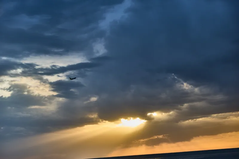 dramatic sunset sky with golden sunlight and airplane silhouette over horizon concept of financial crisis or business uncertainty