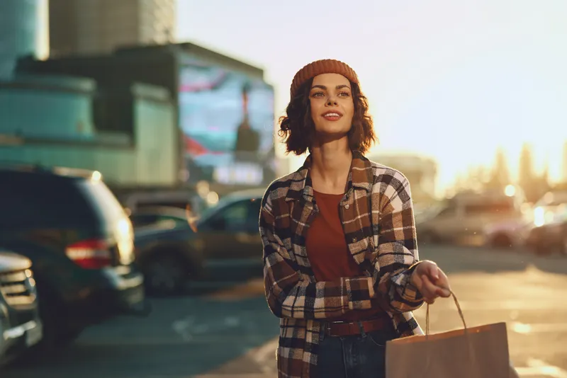 woman shopping urban sunset smile sunlight portrait bag authenticity candid lifestyle golden hour glow mindful living emotional storytelling in a warm modern city moment with relaxed confident energy