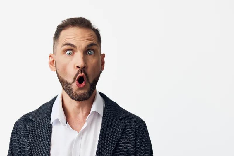 A professional man in business attire displays a surprised emotion on an isolated colored background, creating a strong focal point for corporate stock imagery suitable for presentations and