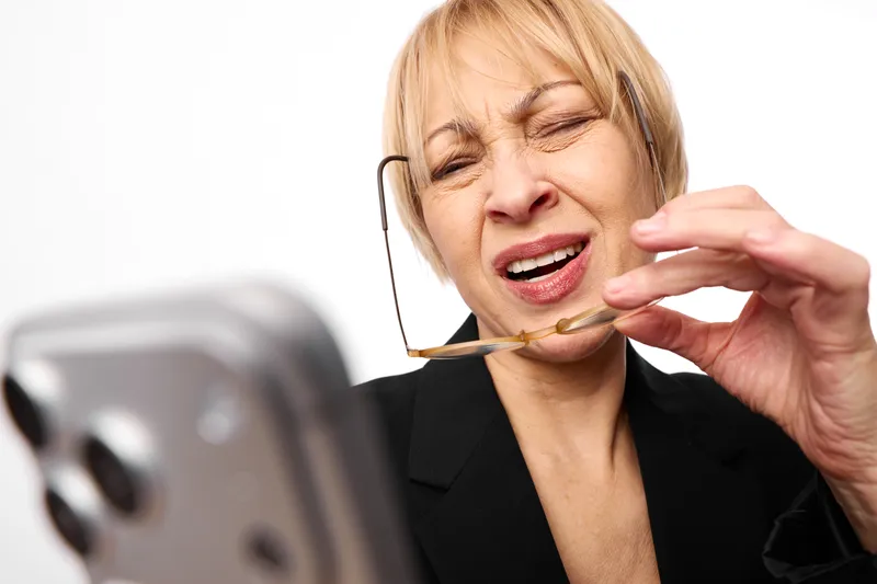 Woman in headset for customer service call, smiling with eyes closed, speaking near microphone, using laptop, bright studio white background, communication