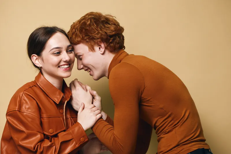 Couple, love, and affection with happy young man and woman smiling and holding hands in warm clothing for relationship and intimacy at home.