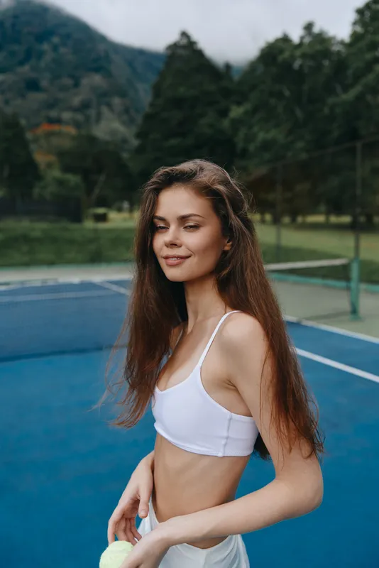 Young woman in activewear enjoying a sunny day on a tennis court, showcasing healthy lifestyle and confidence with a smile