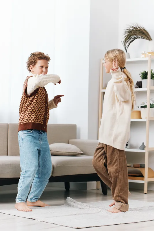 Authentic play scene captures two children in a cozy home room, engaged in a pillow fight, reflecting a school aged lifestyle and genuine imagination in a candid moment.