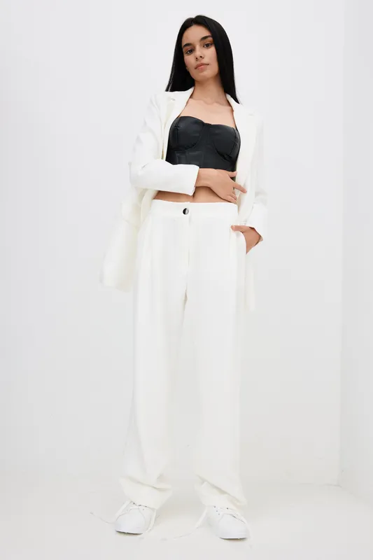 stylish woman in white loose pants and blazer with black top standing confidently against white background, casual contemporary fashion and minimalistic style