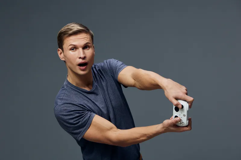 surprised young caucasian man wearing blue t-shirt hold video game controller playing virtual reality game technology entertainment concept