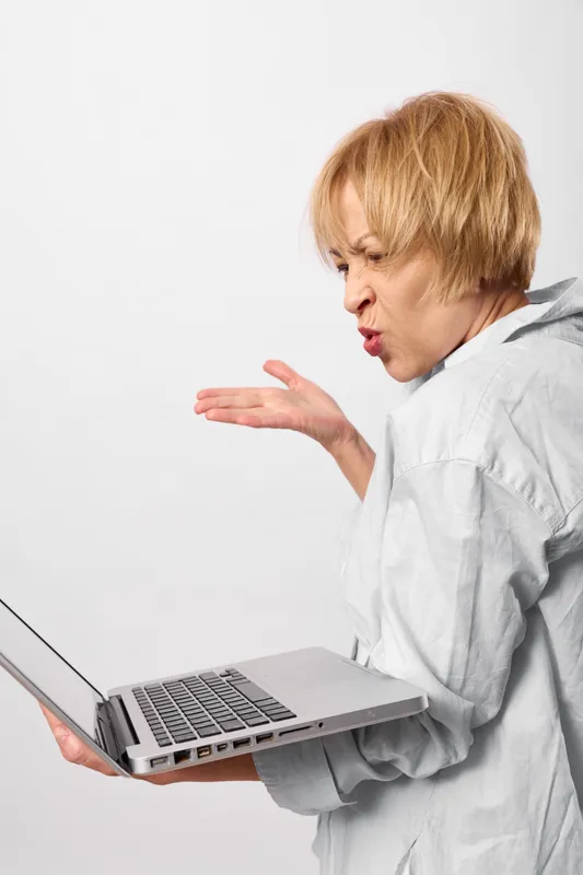 Woman with short hair holds a laptop while coughing, respiratory health, workplace stress, and care are shown. Her hand is raised in a side view on a white studio background. Concept of illness and