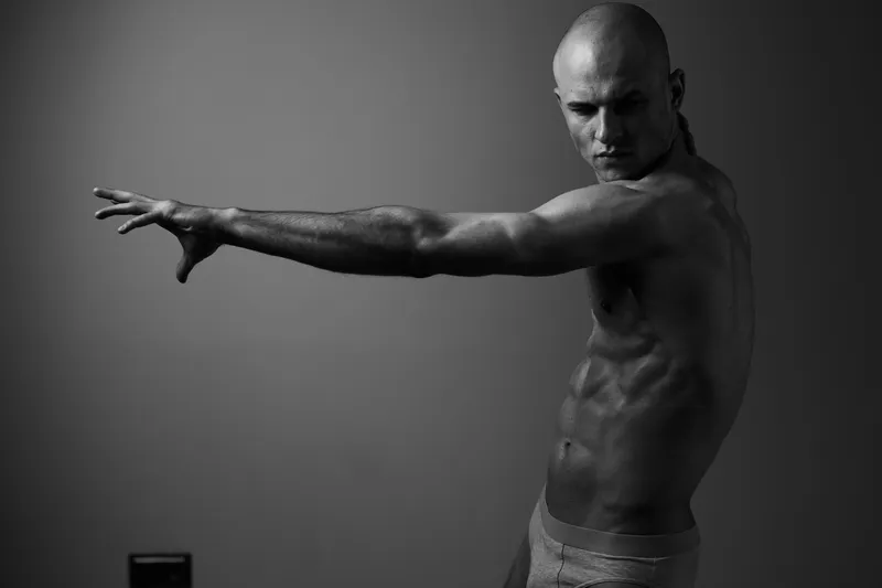 A striking black and white image of a muscular man in an expressive pose, showcasing strength and vitality. Captivating and dynamic, perfect for fitness themes.