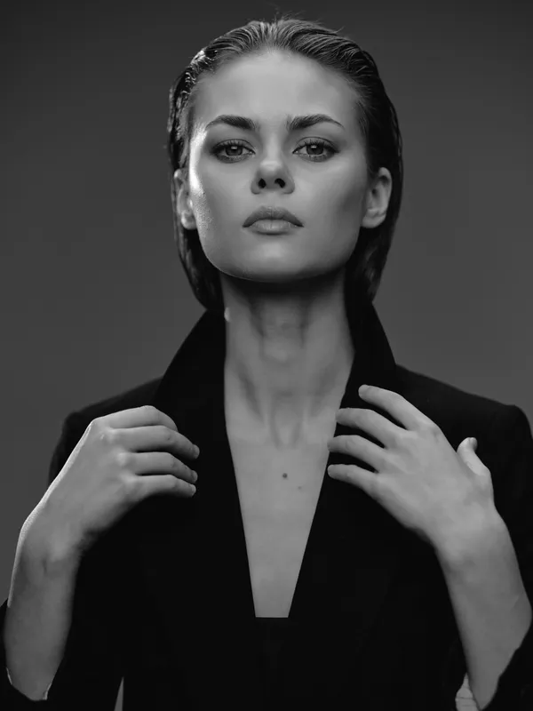 Black and white portrait of a confident woman with wet hair wearing a dark blazer, showing strength and elegance.