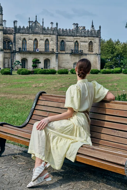 Woman on bench in park in dress facing building authenticity inclusivity