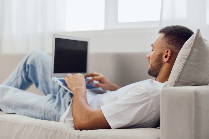 Relaxed man working on a laptop at home, showcasing modern lifestyle, creativity, and productivity in a cozy atmosphere. Ideal for remote work themes.