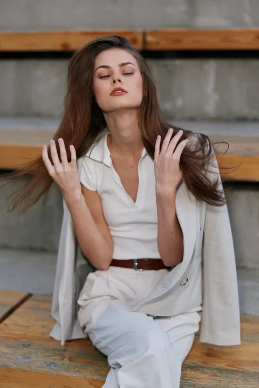 Confident businesswoman in a stylish outfit poses on wooden stairs, showcasing modern business fashion with an elegant touch, exhibiting poise and professionalism.