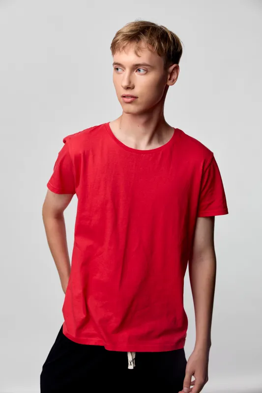 Red tshirt worn by a young man in a casual studio pose, minimalist fashion look with clean background and soft lighting, emphasizing relaxed style and contemporary everyday wear
