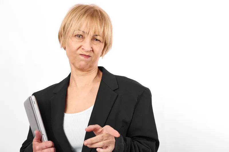 Senior business woman portrait holding smartphone and phone, confident expression, pointing to screen, white studio background, office relaxed posture