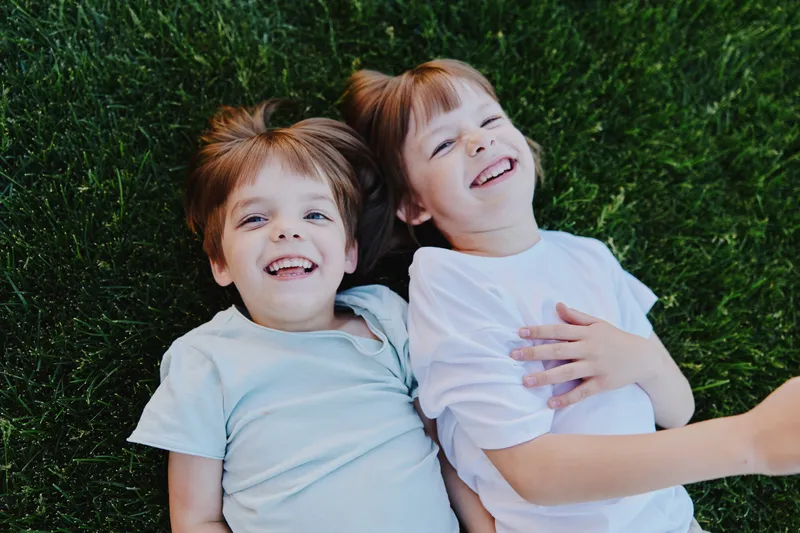 Happy children lying on the grass, enjoying a sunny day outdoors, laughing and playing together, celebrating friendship and joy of childhood.