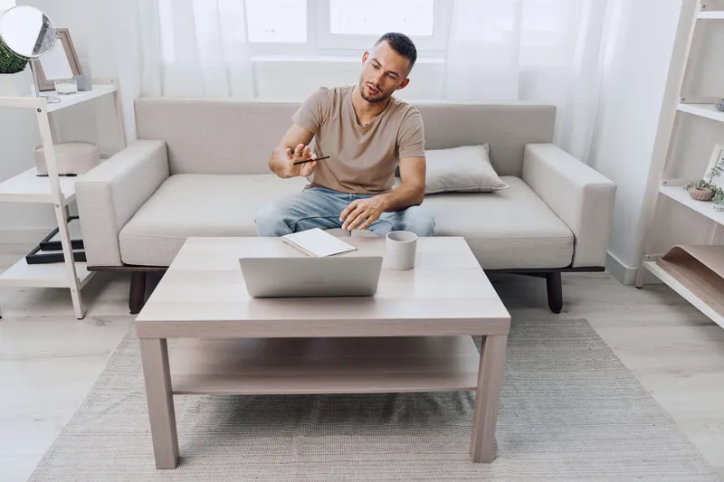 Engaged man working on his laptop at home, dressed casually in a relaxed atmosphere, highlighting modern lifestyle and productivity in a cozy environment.
