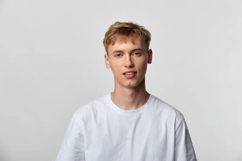 Man, young, casual, white tshirt, studio setting with neutral background, relaxed expression, everyday fashion vibe suitable for lifestyle and model portfolio