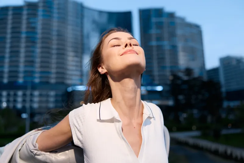 Confident businesswoman enjoying the moment in an urban setting, wearing a stylish outfit with a radiant smile, capturing empowerment and success.
