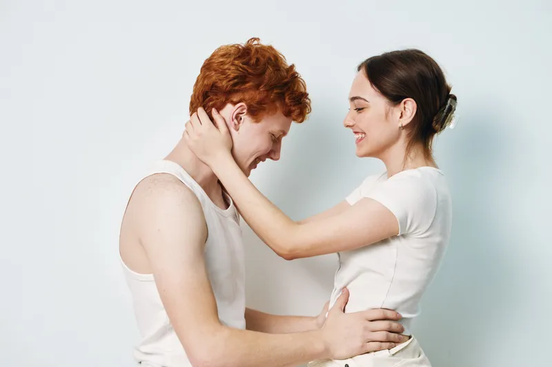 Young couple, woman and man embracing with happy smile, affection, love and connection. Romance, relationship and warmth between two people in casual clothing indoors.