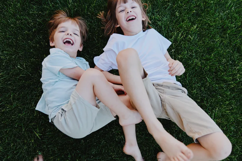 Happy children playing on grass, enjoying a sunny day with laughter and joy. Their playful spirit embodies the essence of carefree childhood moments.
