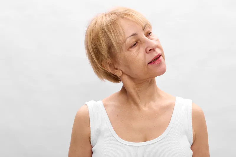 Elderly woman coughing indoors on white studio background, sick respiratory illness grimace, health symptom care medical checkup concept, copy space for message