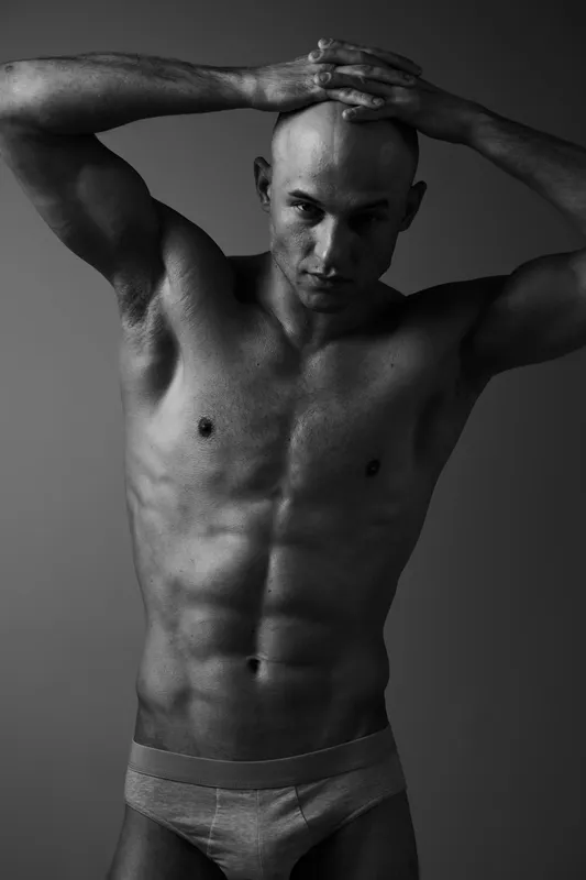 Strong man posing in black and white, showcasing toned physique with confidence and determination. Perfect for fitness and wellness themes.