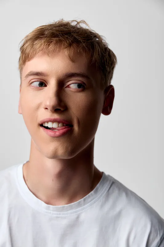 Young man with a thoughtful expression in a casual tshirt, closeup headshot with soft lighting highlighting skin tone for lifestyle, fashion, and editorial photography
