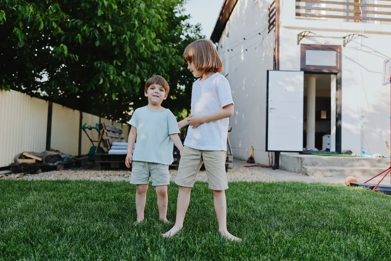 Happy children playing in a green yard, enjoying their time together in a warm summer day. Joy and laughter fill the atmosphere as they interact.