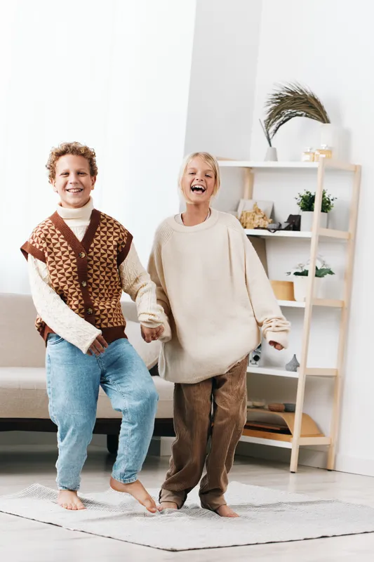 Authentic scene of children at home, a playful moment capturing a theme of play, casual school inspired outfits, and relaxed joy in a candid lifestyle setting.
