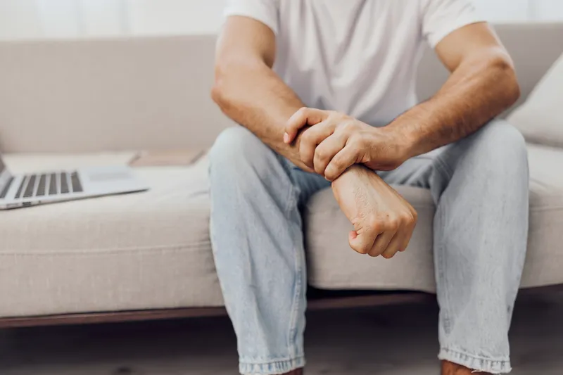 Thoughtful man sitting on a couch with a laptop, reflecting on his ideas and creativity. Casual attire brings a relaxed vibe to the serene atmosphere.