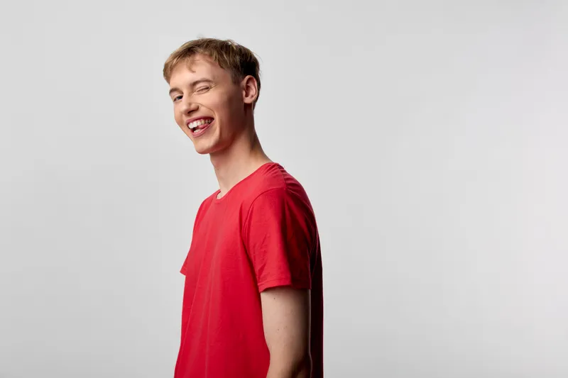 Smiling man in a red tshirt stands in a bright studio, conveying casual confidence and approachable energy, ideal for lifestyle, fashion and advertising campaigns