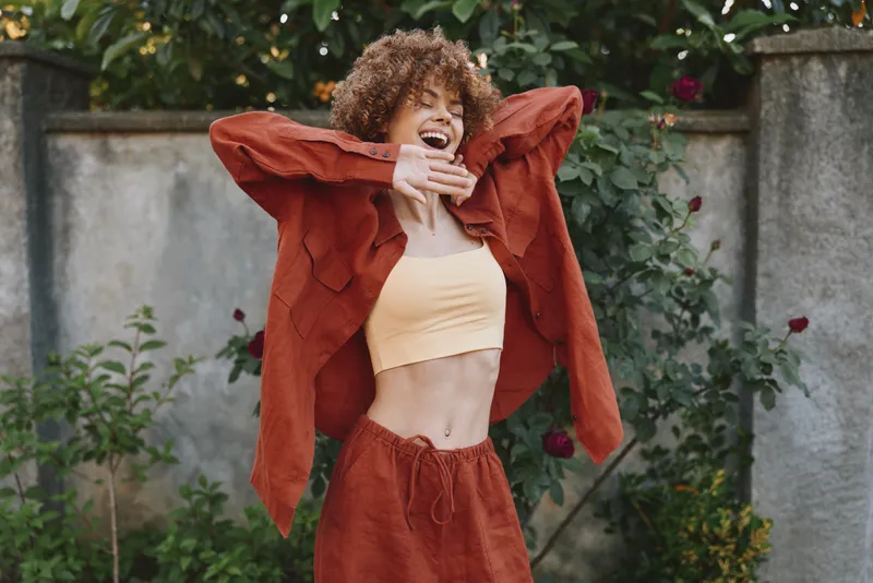 A woman enjoying a vibrant lifestyle outdoors wears a casual jacket and matching pants, smiling with energy. A bright portrait of fashion, happiness, and confidence