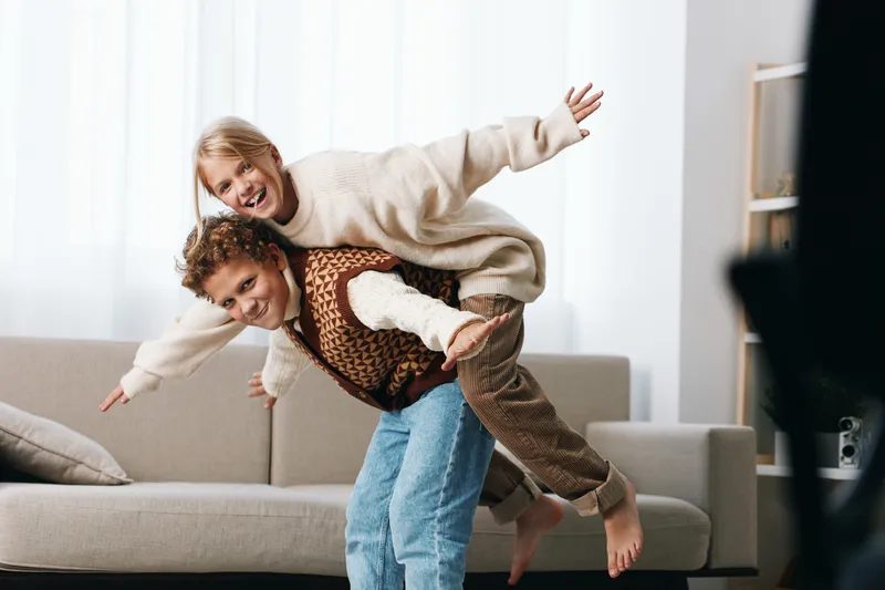 Authentic play scene in a cozy living room captures two kids at play, reflecting school age lifestyle, imagination, and spontaneous energy in motion.