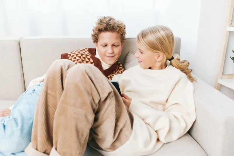 Authentic moment of siblings enjoying a cozy at home scene, blending school life and lifestyle during a relaxed, warm afternoon with natural light.